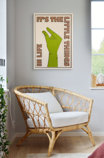 It’s the Little Things in Life wall art featuring a hand making the small sign, with a color palette of green, off-white, and sand. Perfect for minimalist home decor.